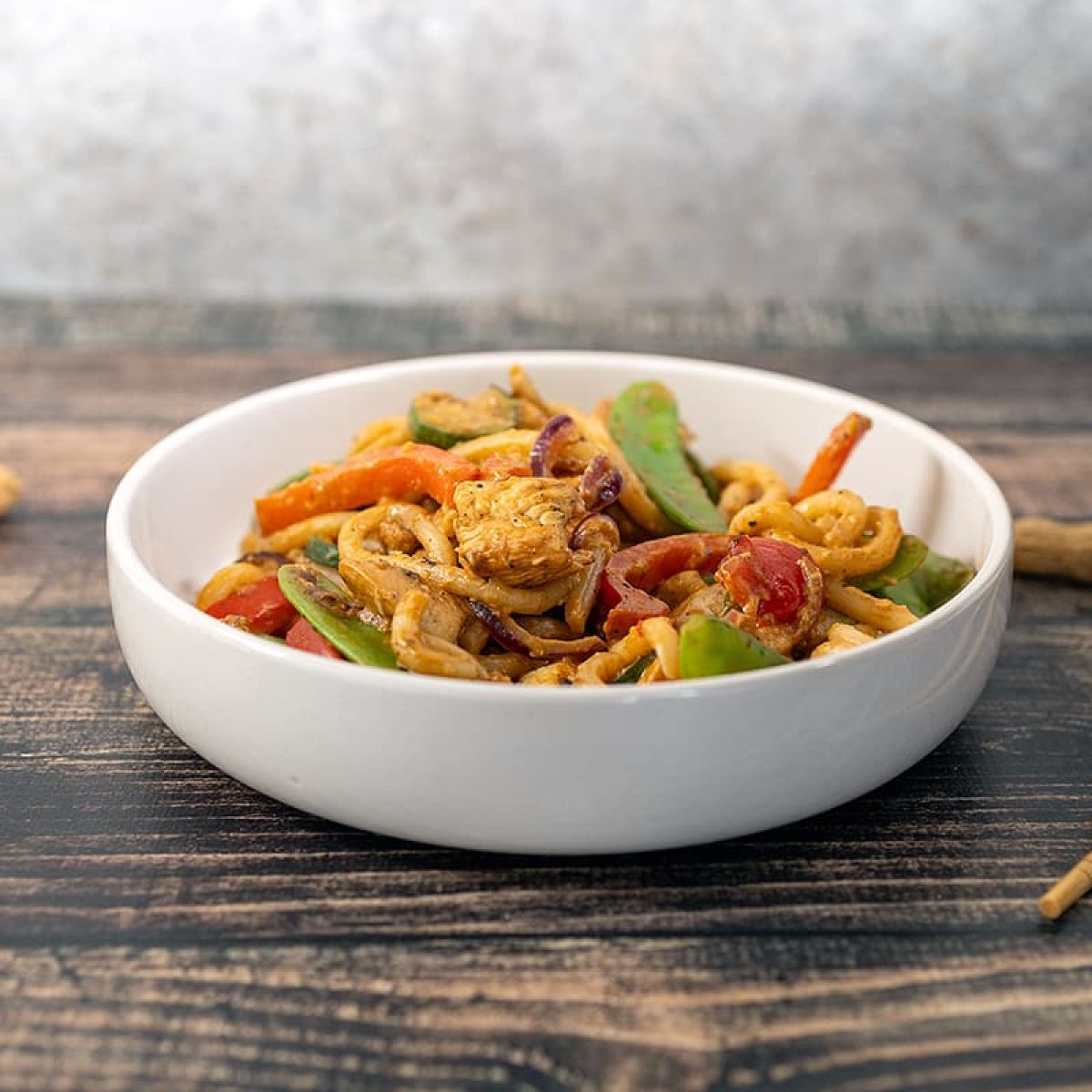 Udon noedels met kip en groenten in een pindasaus