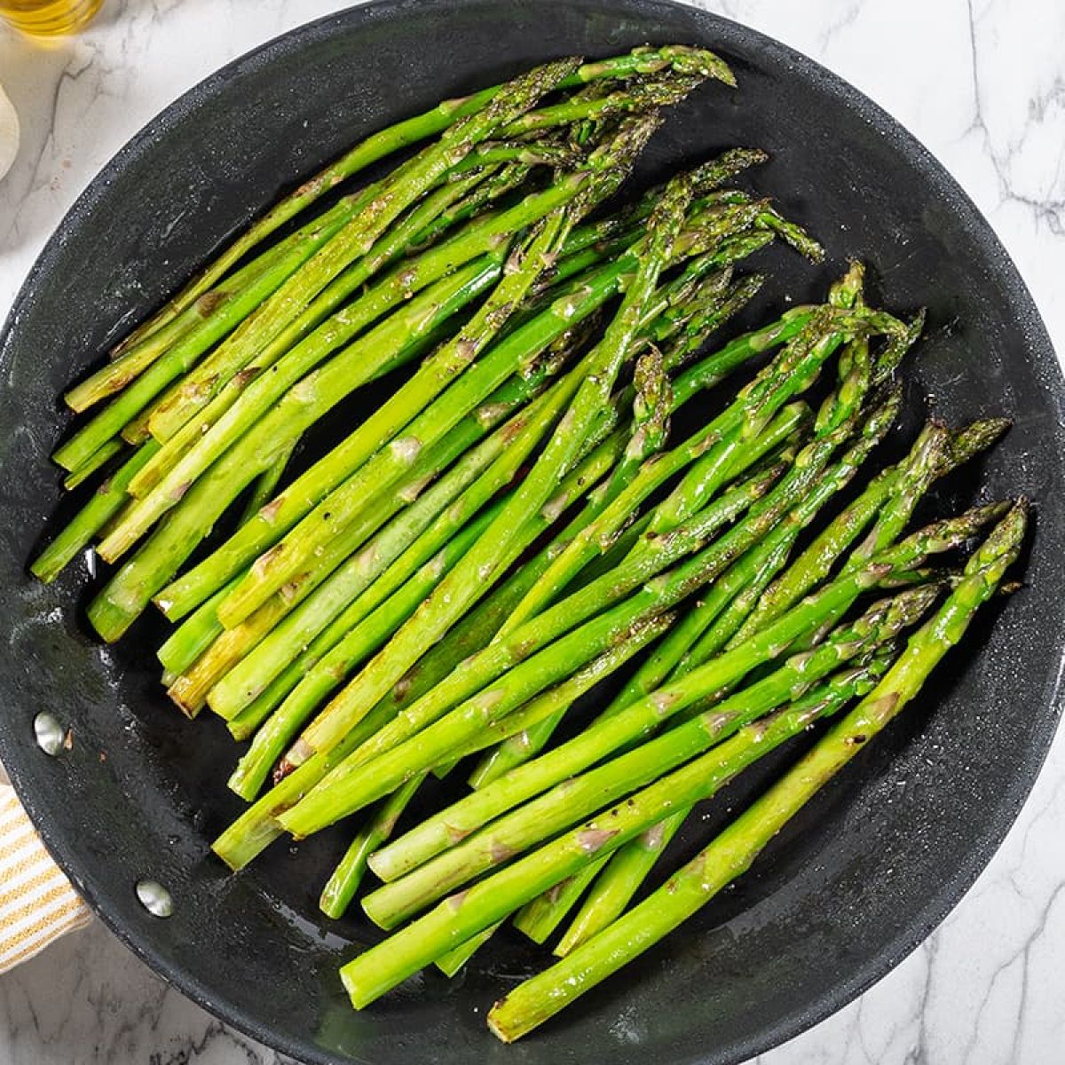 Groene asperges bakken in de pan met een vleugje knoflook
