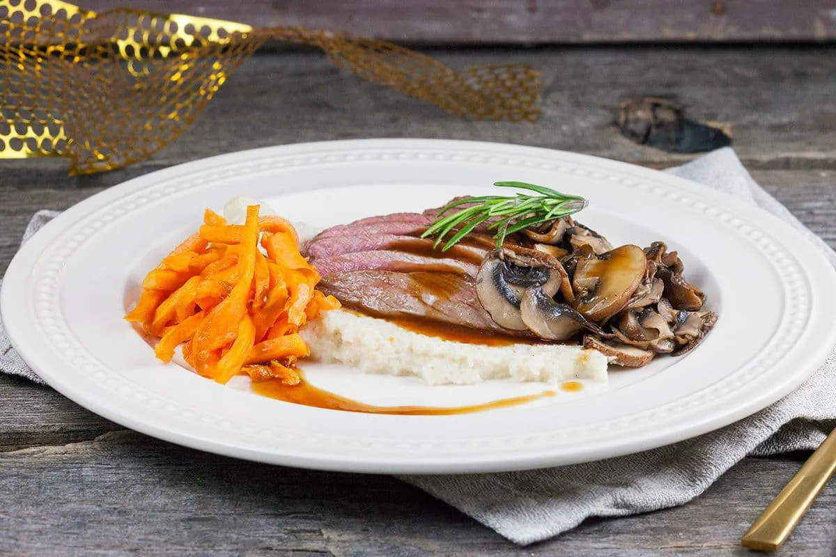 Hertenbiefstuk met geroosterde bloemkoolpuree en zoete aardappelfrietjes