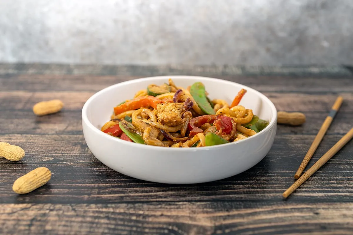 Udon noedels met kip en groenten in een pindasaus