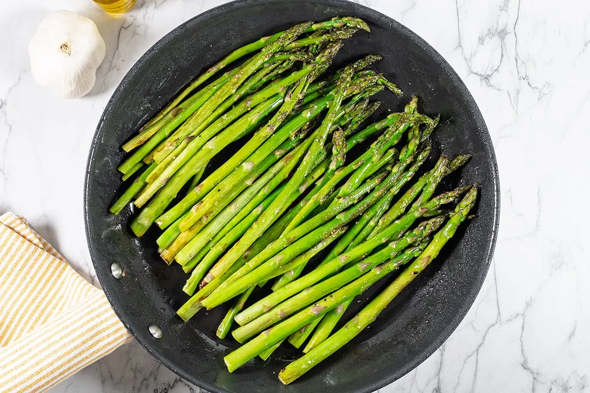 Groene asperges bakken in de pan met een vleugje knoflook