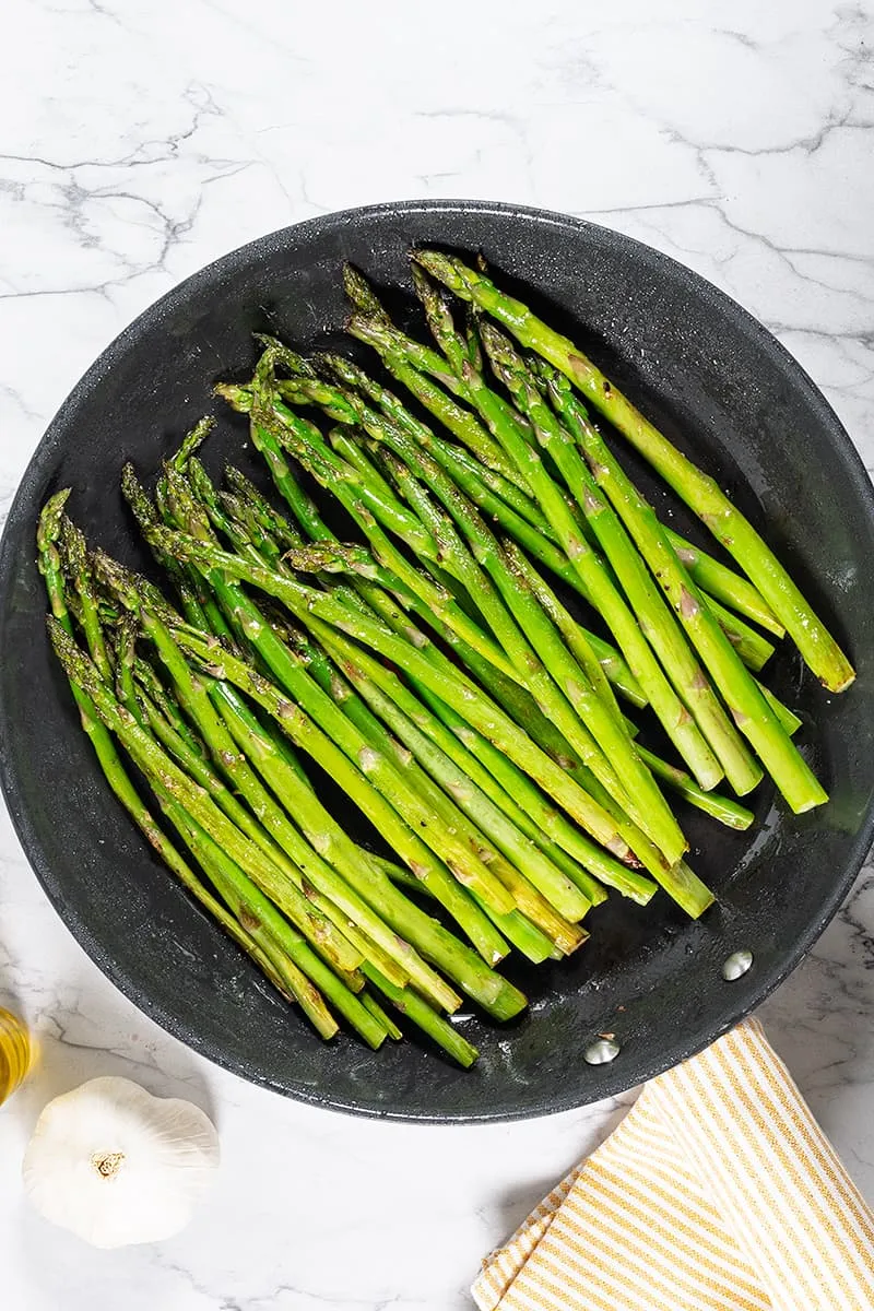 Groene asperges bakken in de pan met een vleugje knoflook